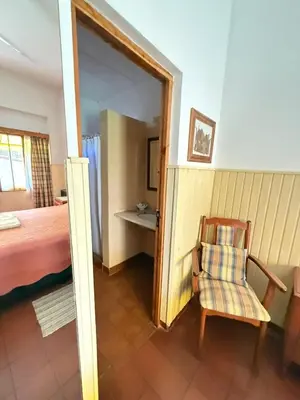 a bedroom with a bed and a chair in a room at Alta Montaña Hosteria&Apart in Los Hornillos