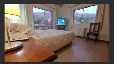 a bedroom with a bed and a table and a desk with a lamp at Casa en las sierras de Merlo in Merlo
