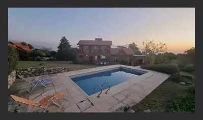 a house with a swimming pool in front of a house at Casa en las sierras de Merlo in Merlo