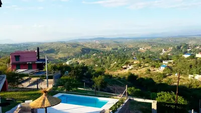 a villa with a swimming pool and mountains in the background at Cabaña Punta Piedras in Villa Carlos Paz