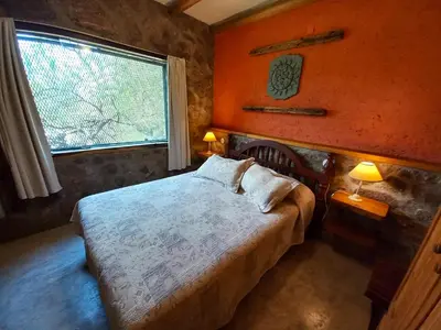 a bedroom with a bed with two lamps and a window at Cabaña Punta Piedras in Villa Carlos Paz