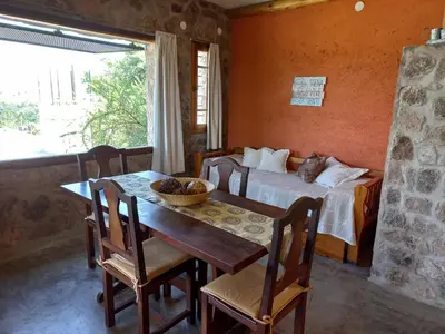 a dining room with a table and a bed at Cabaña Punta Piedras in Villa Carlos Paz