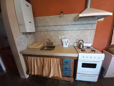a small kitchen with a stove and a sink at Cabaña Punta Piedras in Villa Carlos Paz