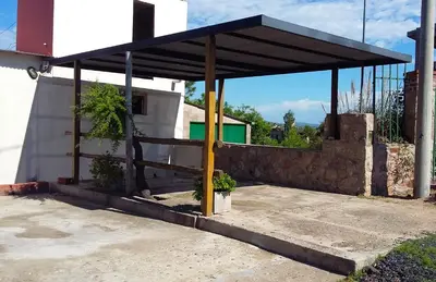 a building with a pavilion on the side of it at Cabaña Punta Piedras in Villa Carlos Paz
