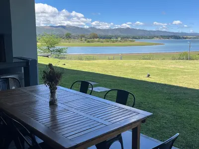 a wooden table on a porch with a view of a lake at Puerto del Águila Departamento con vista al lago- The View Luxuary Aparts in Potrero de Garay