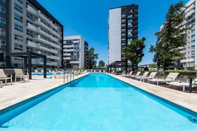 a large swimming pool with chairs and buildings at Departamento Amoblado Premium en Opera Luxury in Cordoba