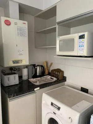a kitchen with a washing machine and a microwave at Departamento Amoblado Premium en Opera Luxury in Cordoba