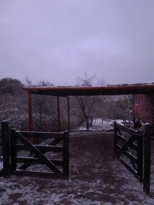 a wooden pavilion with a fence in the snow at La casita de la montaña in El Parador