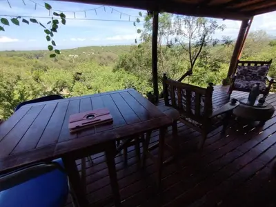 a wooden table and chairs on a deck with a view at La casita de la montaña in El Parador