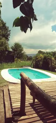 a swimming pool next to a wooden deck at Cabaña en los solares in Villa Ciudad Parque