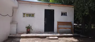 a house with a black door and a wooden bench at Departamento en Villa Santa Cruz del Lago in Villa Santa Cruz del Lago