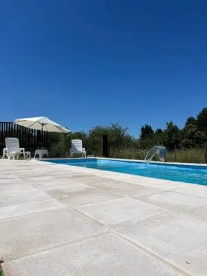a swimming pool with two chairs and an umbrella at Chalet en Potrero de Garay in La Estancia