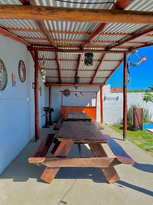 a group of wooden picnic tables under a roof at COMPLEJO AyH in Malagueño