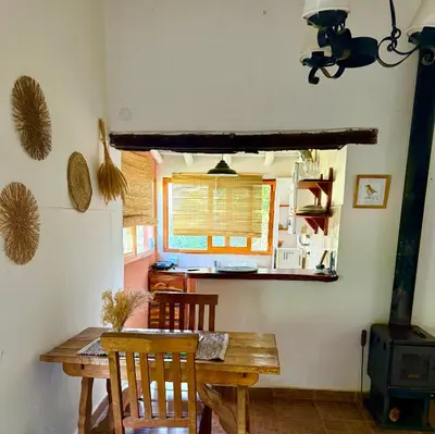 a dining room with a wooden table and a kitchen at Casita de campo La Añurita in San Javier