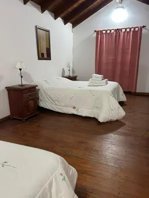 a bedroom with two beds and a wooden floor at Cabañas Costa Alta in Mina Clavero