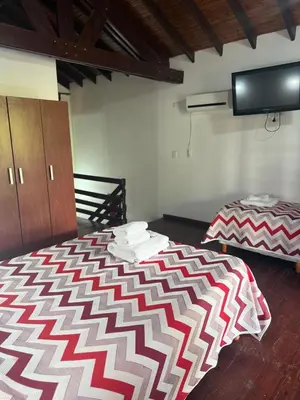 a bedroom with a bed and a flat screen tv at Cabañas Costa Alta in Mina Clavero