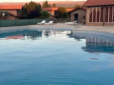 a swimming pool with blue water in a yard at Cabañas Costa Alta in Mina Clavero