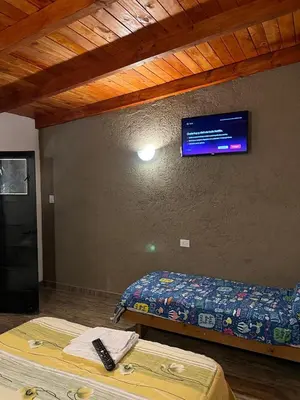 a room with two beds and a tv on the wall at Hospedaje Malvinas in Alta Gracia