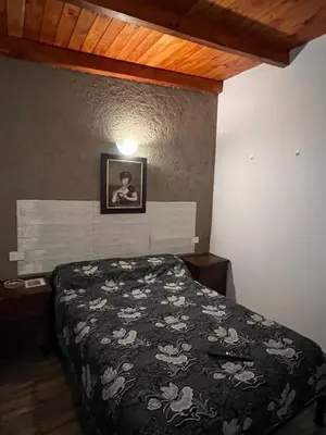 a bedroom with a bed with a black comforter at Hospedaje Malvinas in Alta Gracia