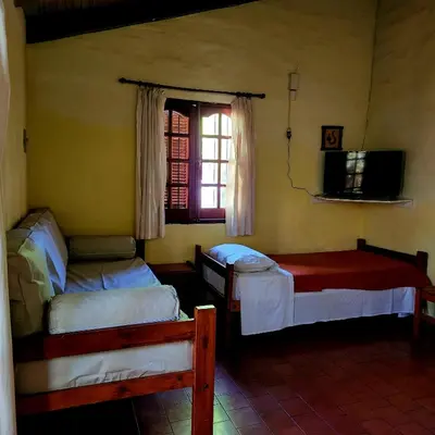 a room with two beds and a window and a tv at Los Zarzos in Mina Clavero