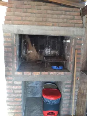a brick fireplace with a red stool and a bench at Departamento Loma Hermosa in Santa Rosa de Calamuchita