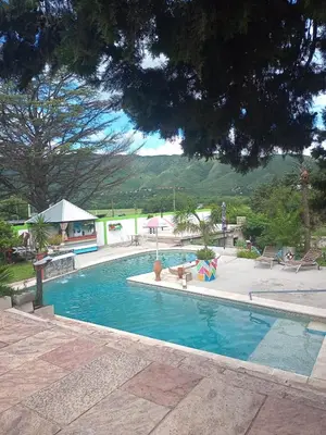 a swimming pool with chairs and umbrellas at Casas y Chalets Privados Valle del Reposo in Bialet Massé