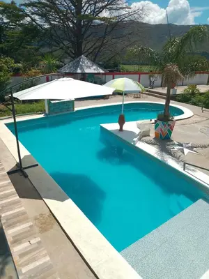 a swimming pool with blue water and an umbrella at Casas y Chalets Privados Valle del Reposo in Bialet Massé