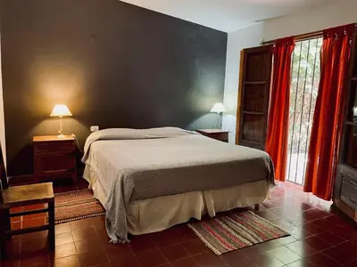 a bedroom with a large bed and red curtains at Casa de campo La Añurita in San Javier
