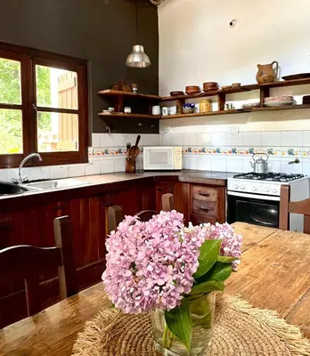 a kitchen with a table with a vase of pink flowers at Casa de campo La Añurita in San Javier