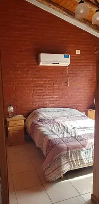 a bed in a room with a brick wall at Cabañas Valle del Chutunzo in San Francisco del Monte de Oro