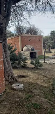 a brick building with a grill in a yard at Cabañas Valle del Chutunzo in San Francisco del Monte de Oro