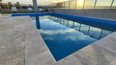 a pool with a reflection of the sky in the water at Departamentos Premium Opera in Villa Carlos Paz