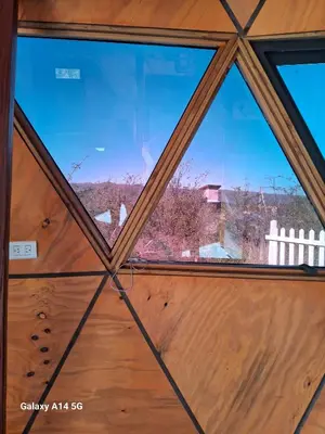 a view through aorthole window of a wooden door at Domo Del Rio in Los Reartes
