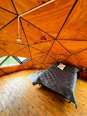 a bed in a room with a wooden ceiling at Domo Del Rio in Los Reartes
