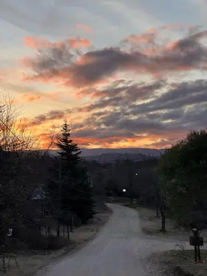 a dirt road with a sunset in the sky at Cabaña Carmanqui in Alpa Corral