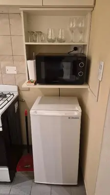 a small kitchen with a microwave and a refrigerator at Depto Centro con Patio Pet Friendly La Cañada in Cordoba