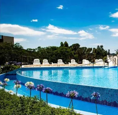 a large swimming pool with white chairs and flowers at Veneto Village in Villa Parque Siquiman