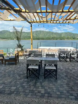 a group of tables and benches under a pavilion near the water at Veneto Village in Villa Parque Siquiman