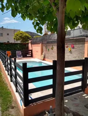 a fence around a swimming pool with a tree at La tranquera Carlos Paz in Villa Carlos Paz