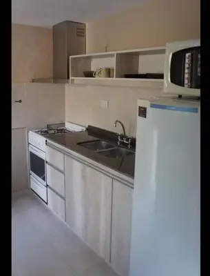 a kitchen with a sink and a stove and a refrigerator at La tranquera Carlos Paz in Villa Carlos Paz