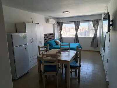 a kitchen and dining room with a table and a blue couch at Monoambiente cómodo zona centro in Cordoba