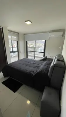 a bedroom with a black bed and a chair at Miralejos 7 in Villa Carlos Paz