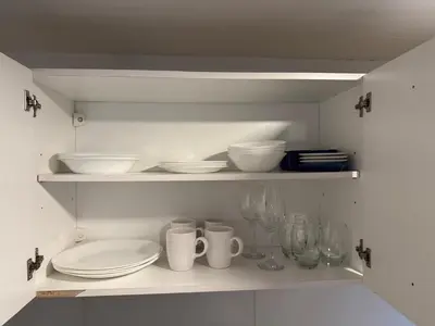 a white cabinet with plates and bowls and glasses at Stanza Córdoba, Heriberto Martinez, Villa Belgrano in Cordoba