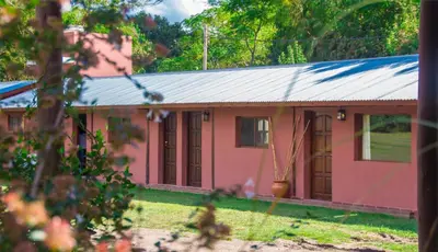 a pink house with a tin roof at La Casona Cabañas in Villa Ciudad Parque