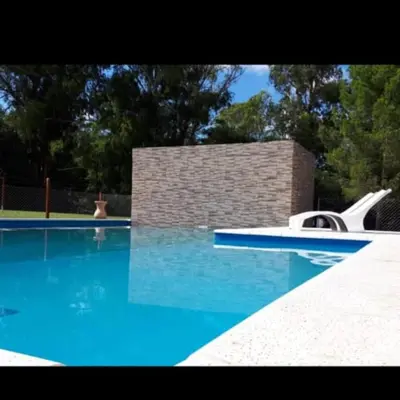 a swimming pool with blue water and a slide in it at La Casona Cabañas in Villa Ciudad Parque