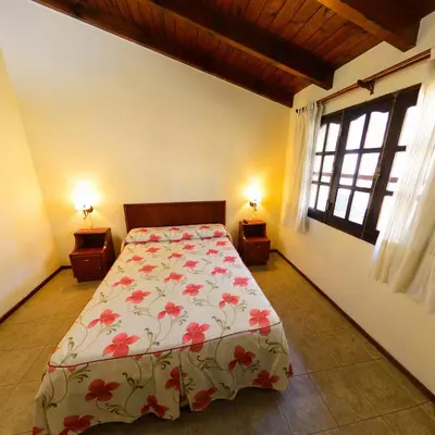 a bedroom with a bed with a floral bedspread at Pinar del Arroyito in Villa General Belgrano