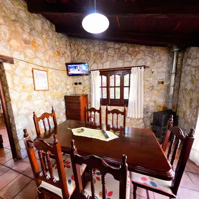 a dining room with a wooden table and chairs at Pinar del Arroyito in Villa General Belgrano