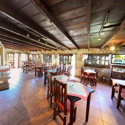a restaurant with tables and chairs in a room at Pinar del Arroyito in Villa General Belgrano
