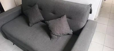 a gray couch with three pillows on it at Departamento sol in Cordoba