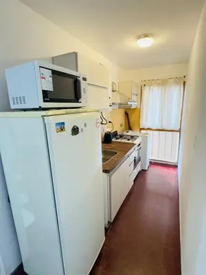a kitchen with a white refrigerator and a microwave at Gral paz Dpto completo con cama queen y seguridad in Cordoba